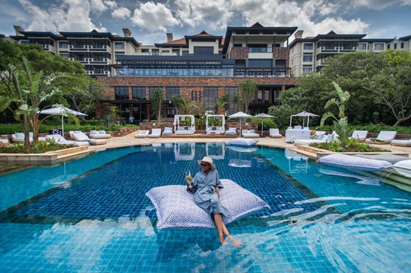 The Capital Zimbali hotel with a lady sitting on a floating pillow in the pool