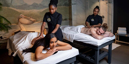 Des clients profitant de massages du corps entier prodigués par des thérapeutes dans une salle de soins apaisante
