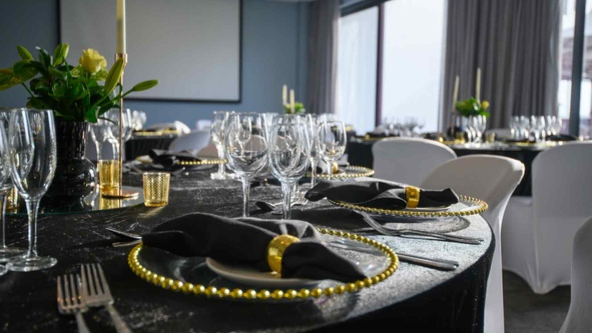 Event table set for a celebration with black linen, gold-rimmed plates and glassware