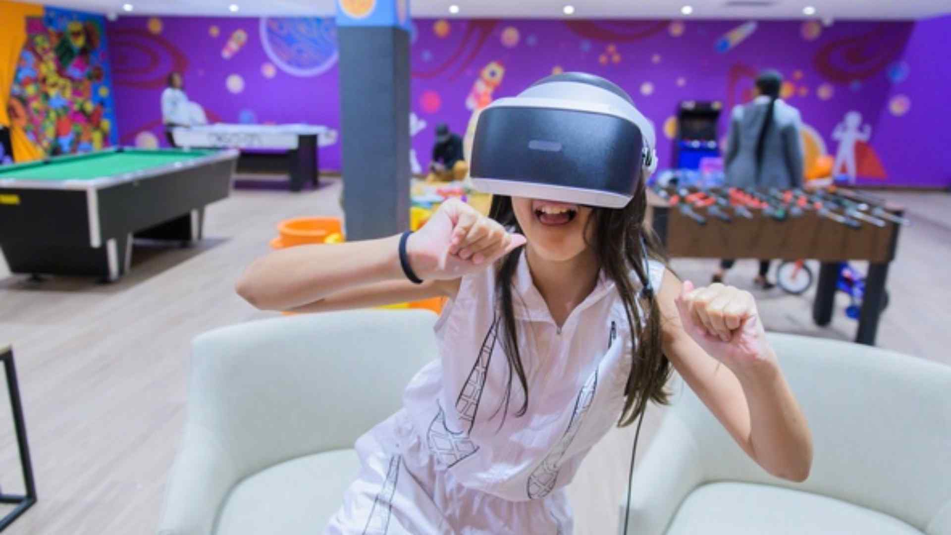 Girl playing a virtual reality game in a games room with pool and foosball tables