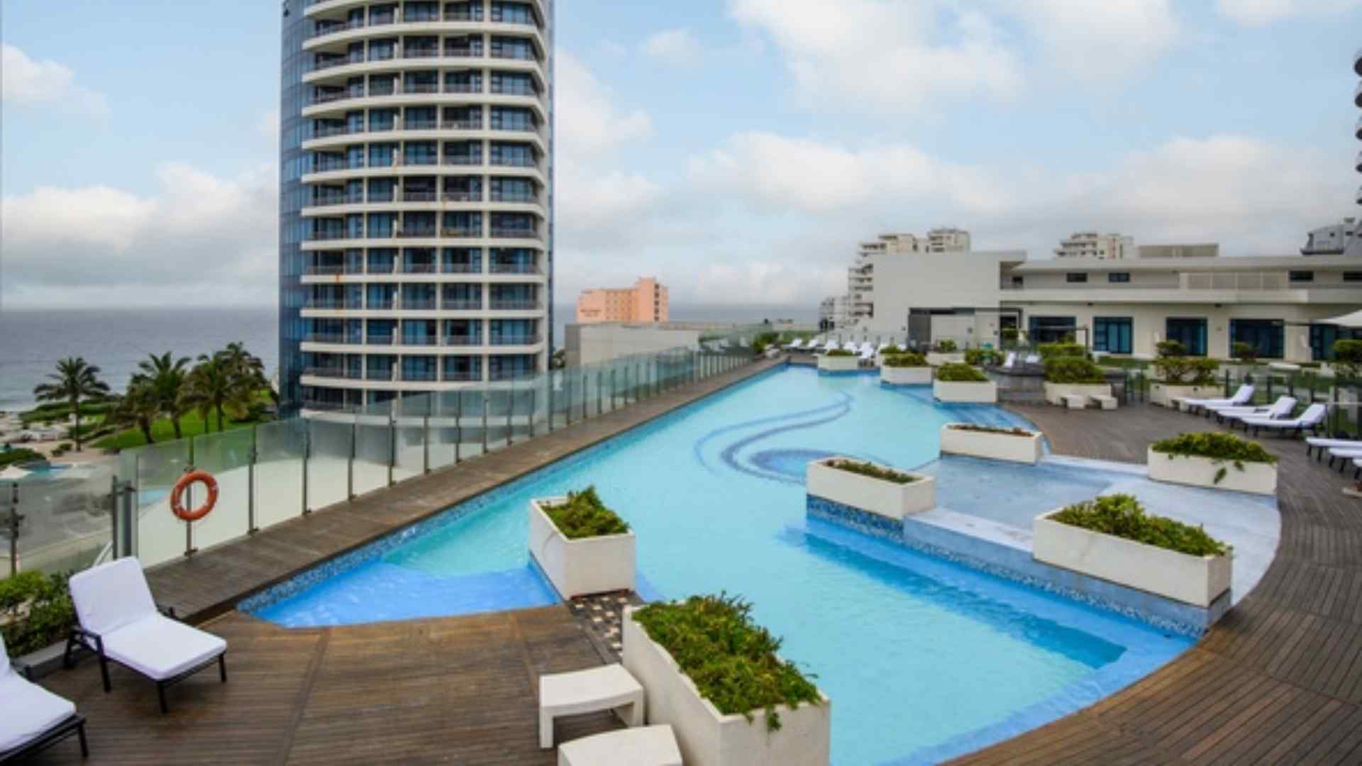 Outdoor hotel pool deck with sun loungers overlooking the sea